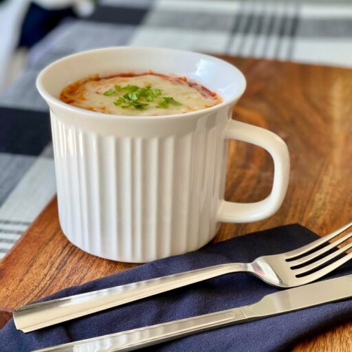 A single CorningWare mug with a coffee cup and saucer on a wooden table.