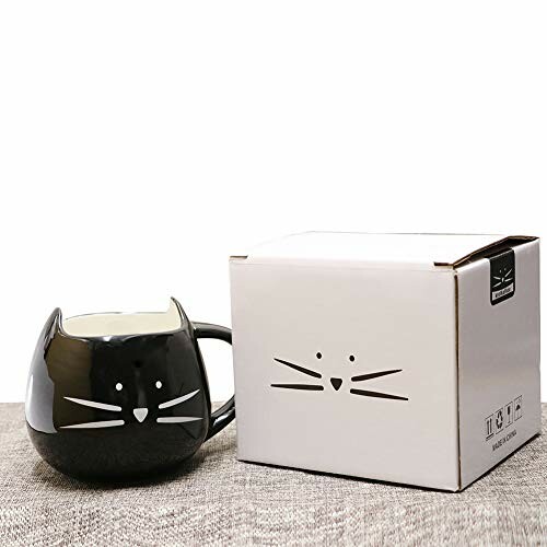 Cat-shaped black mug with tea and sweets on a table.