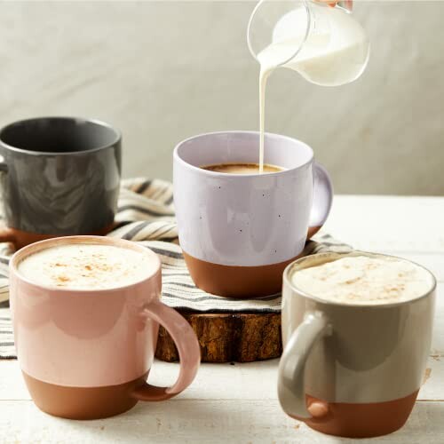 Assorted mugs with coffee and milk being poured.