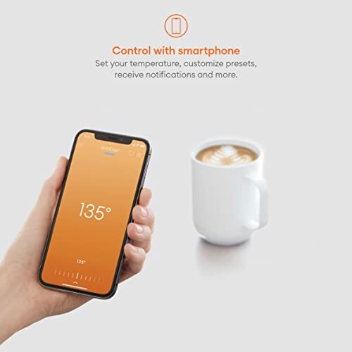 Hand holding smartphone displaying 135 degrees next to a mug of coffee.