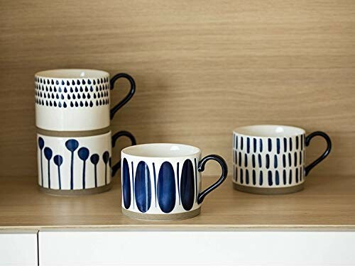 Four ceramic mugs with blue patterns on a shelf.