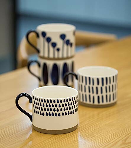 Stack of three decorative mugs with blue designs on a wooden table.